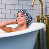 Model relaxing in bathtub wearing Grace & Company Casablanca shower cap, with shower cap visible