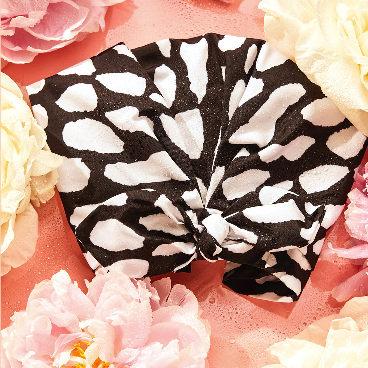 Casablanca shower cap surrounded by coral and ivory flowers, showing the bow and printed fabric